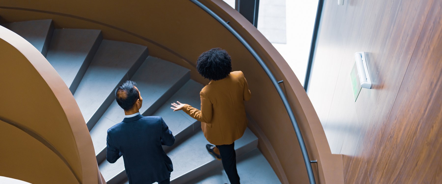 two people walking up stairs in office building